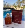 Fragrance World Proud Of You Amber EDP 100 ml — product in een gestileerde setting; zeer nabije close-up; tussen groen