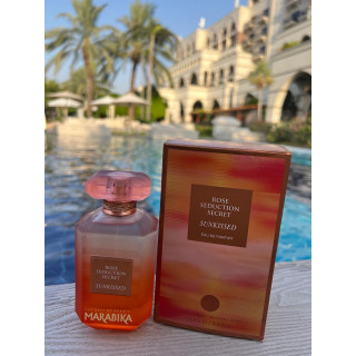 Fragrance World Rose Seduction Secret Sunkissed EDP 100 ml — toode stiliseeritud keskkonnas; väga lähivõte; roheluse keskel