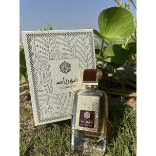 Lattafa Perfume Shahrazad EDP 100 ml — toode stiliseeritud keskkonnas; väga lähivõte; roheluse keskel; lähim kadreering
