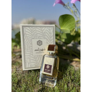 Lattafa Perfume Shahrazad EDP 100 ml — toode stiliseeritud keskkonnas; väga lähivõte; roheluse keskel; keskmine kadreering