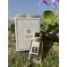 Lattafa Perfume Shahrazad EDP 100 ml — toode stiliseeritud keskkonnas; väga lähivõte; roheluse keskel; keskmine kadreering