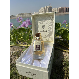 Lattafa Perfume Shahrazad EDP 100 ml — toode stiliseeritud keskkonnas; väga lähivõte; roheluse keskel; kõige laiem kadreering